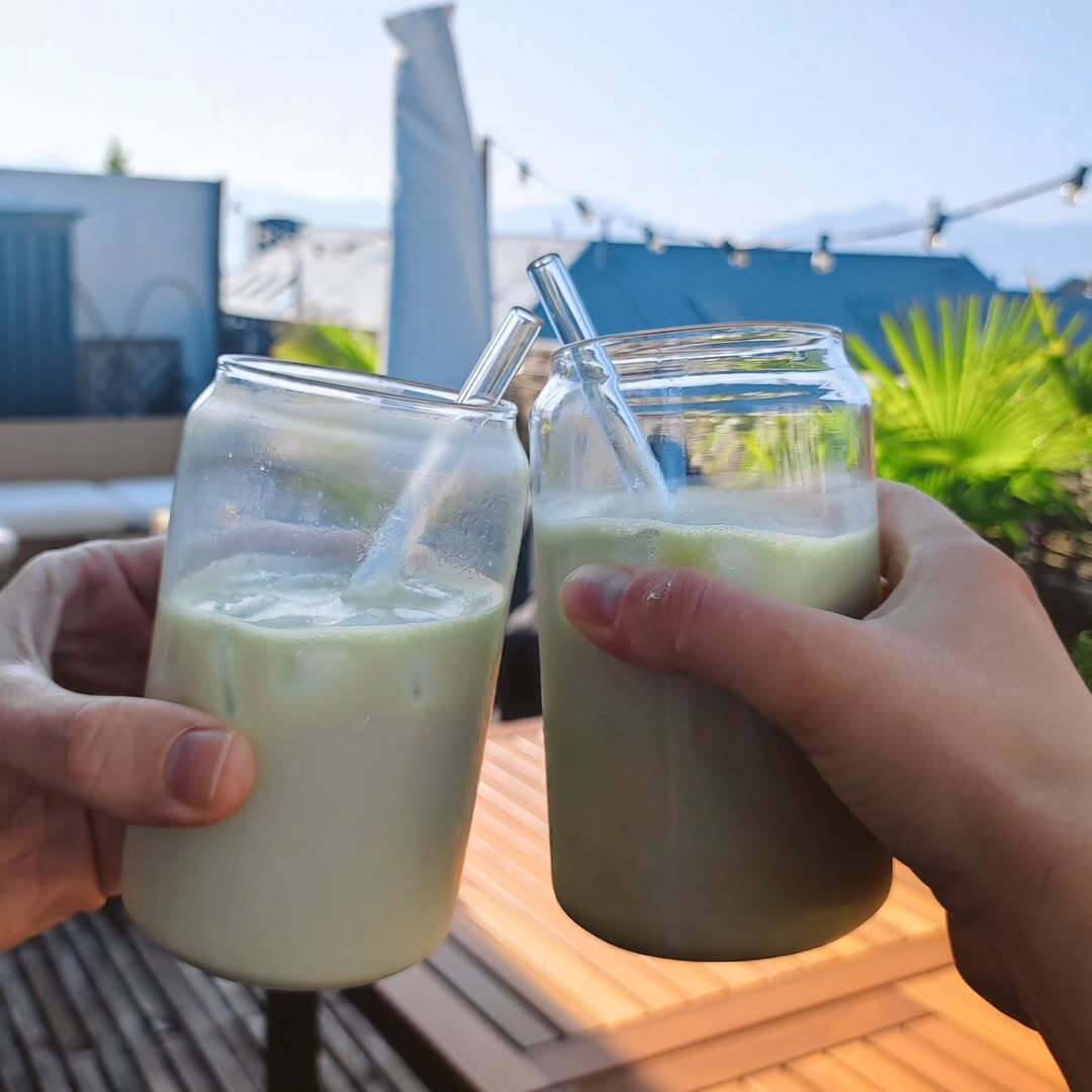 Deux verres de matcha latte en train de trinquer, symbolisant la convivialité et le raffinement de notre thé premium en Suisse.